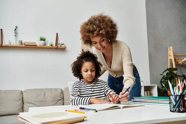 Une mère afro-américaine aide amoureusement sa fille avec ses devoirs, créant un lien et favorisant l'apprentissage. — Photo de stock