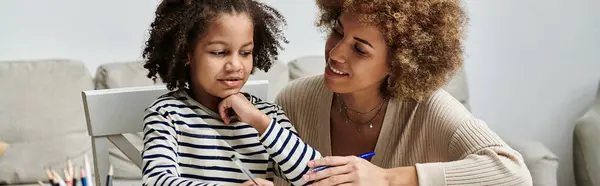 A happy African American mother helps her daughter draw a picture, spending quality time together at home. — Stock Photo