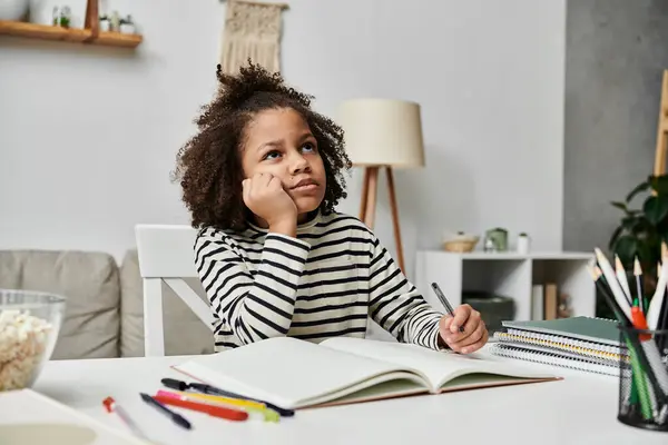 A little girl engrossed in an open book while sitting at a table, exploring the wonders of literature — Stock Photo