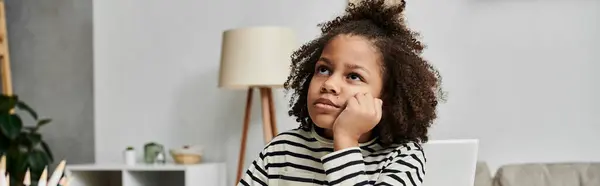 An African American girl sits at a table, dreaming and looking away — Stock Photo