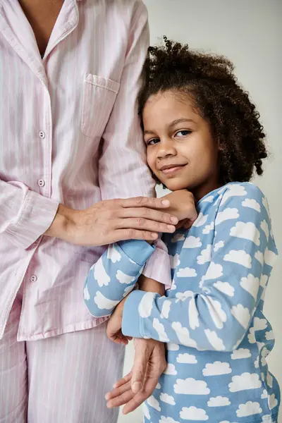 Happy African American mother and daughter in pajamas enjoying quality time together on a grey background. — Stock Photo