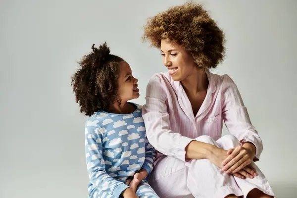 A happy African American mother and daughter in pajamas sitting on the floor together in a cozy setting. — Stock Photo