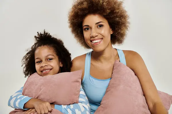 Happy African American mother and daughter in pajamas pose on grey background. — Stock Photo