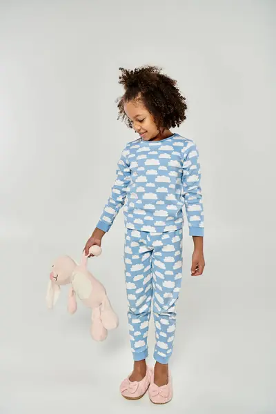 Bambina in pigiama blu custodisce il suo orsacchiotto di peluche — Foto stock