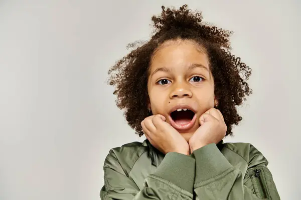 A curly African American girl in stylish clothes holding her hands in front of her face. — Stock Photo