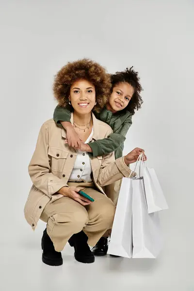 A stylish curly African American mother and son holding shopping bags on a white background. — Stock Photo