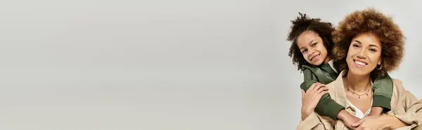 A curly African American mother and her daughter stylishly pose in front of a white background. — Stock Photo