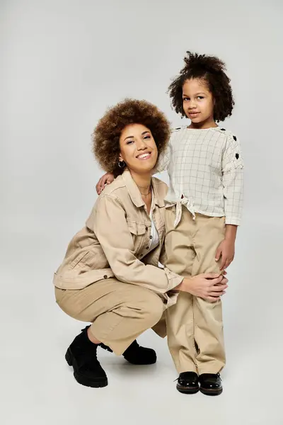 Stylish curly African American mother and daughter posing elegantly against a grey backdrop. — Stock Photo