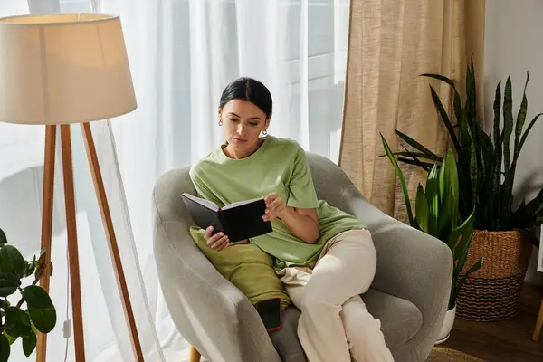 A woman immersed in a book while seated in a chair. — Stock Photo