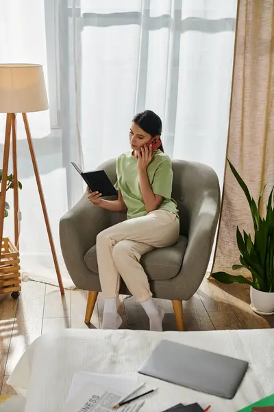 Una mujer con atuendo casual hablando en un teléfono celular mientras está sentada en una silla. - foto de stock