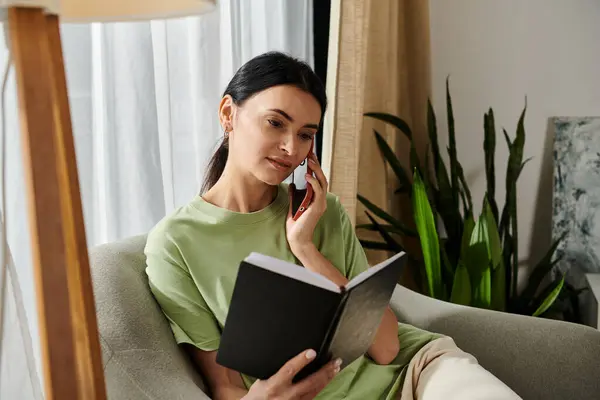 Woman lounging on couch, reading book and chatting on phone. — Stock Photo