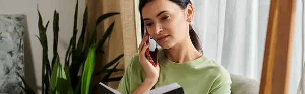 Donna che parla al cellulare mentre tiene in mano un libro. — Foto stock