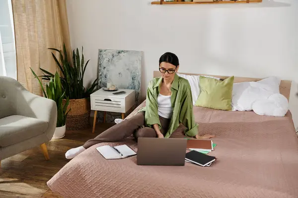 Uma mulher sentada em uma cama, focada em sua tela de laptop. — Fotografia de Stock