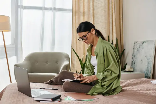 Frau in Freizeitkleidung arbeitet am Laptop auf einem Bett. — Stockfoto