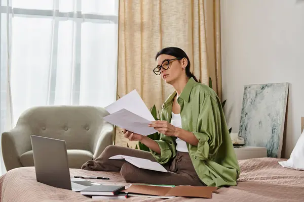 Eine Frau in legerer Kleidung sitzt auf einem Bett, tief in die Lektüre einer Zeitung vertieft. — Stockfoto