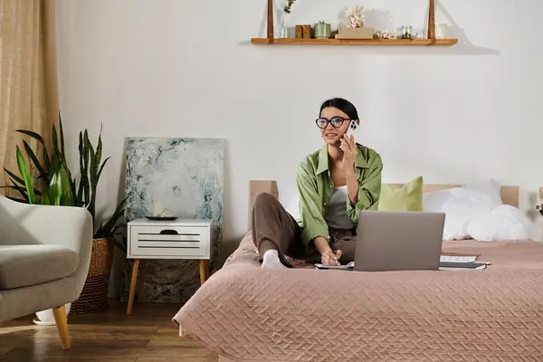 A person sitting on a bed, using a laptop for remote work. — Stock Photo