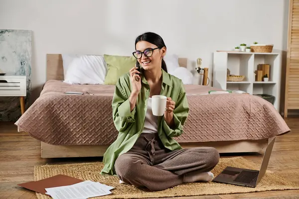 A woman in casual attire peacefully sits on the floor, holding a cup of coffee. — Stock Photo
