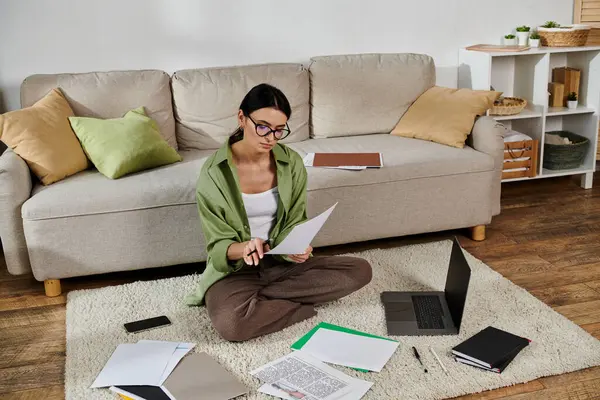 Woman sits on floor in front of laptop, focused on freelance work. — Stock Photo