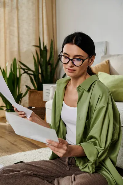 Frau in legerer Kleidung sitzt auf Couch und liest Dokument aufmerksam. — Stockfoto