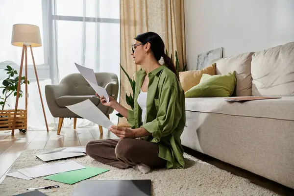 A woman in casual attire sits on the floor absorbed in reading a piece of paper. — Stock Photo
