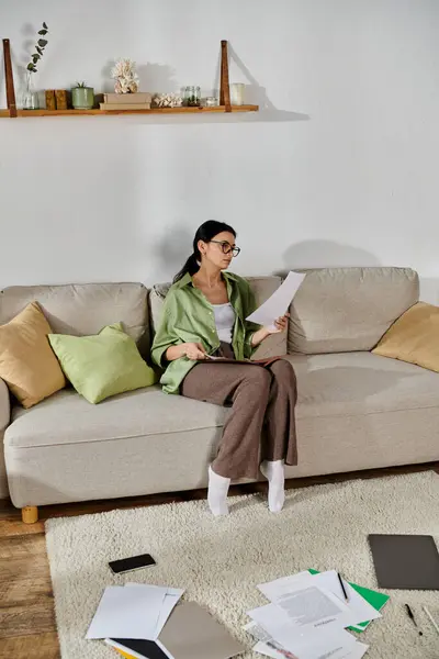 Mujer con atuendo casual leyendo papel en un sofá. - foto de stock