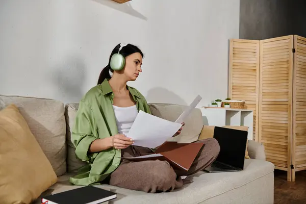 Mujer disfrutando de la música en los auriculares mientras toma un descanso en el sofá. - foto de stock