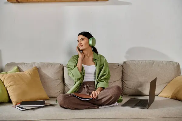 Woman in casual attire sitting on couch, listening music and working remotely. — Stock Photo