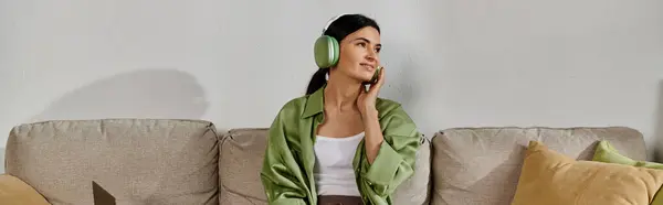 Woman in casual attire relaxing on couch while listening to headphones. — Stock Photo