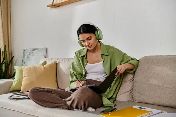 Woman in casual attire listening to headphones on couch. — Stock Photo