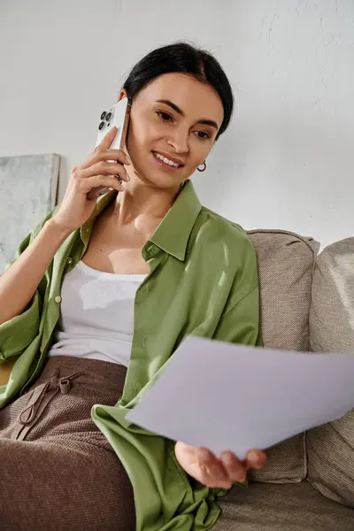 Woman in casual attire relaxing on couch, engrossed in phone chat. — Stock Photo