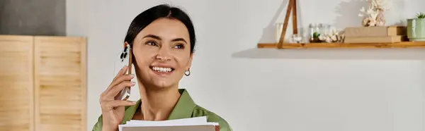 Lässige Frau balanciert zu Hause zwischen Telefonaten und Papieren. — Stockfoto