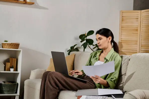 Woman working on laptop while seated on couch. — Stock Photo