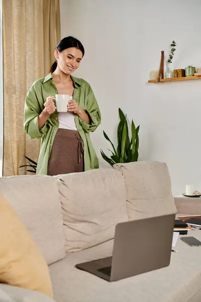 Donna in piedi in soggiorno con tazza di caffè. — Foto stock