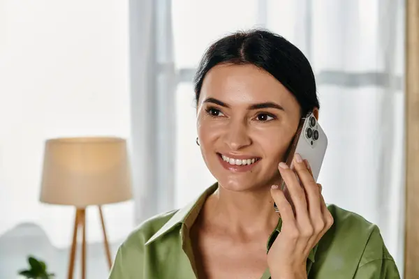Una donna in abbigliamento casual parla su un telefono cellulare in un accogliente soggiorno. — Foto stock