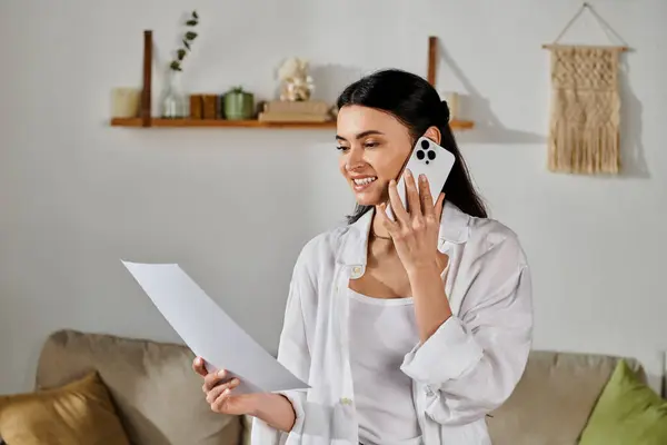 Woman in casual attire multitasking with a cell phone and paper. — Stock Photo