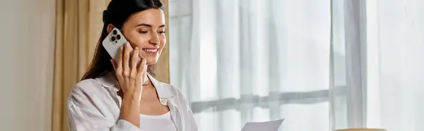 Casual woman talking on cell phone by window. — Stock Photo