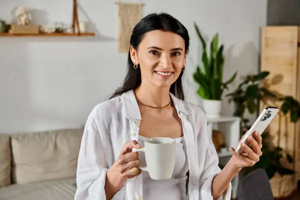 Mujer hermosa multitarea con taza y teléfono. - foto de stock