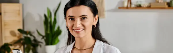 Una donna elegante che sorride alla macchina fotografica mentre lavora da casa. — Foto stock