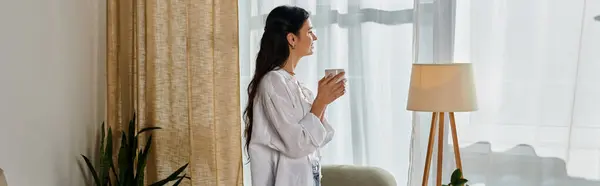 Casual home office scene; woman enjoying coffee by window. — Stock Photo