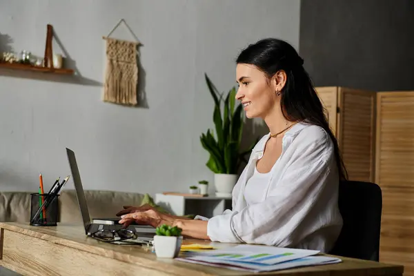 A woman sits at a desk, intensely focused on her laptop. — Stock Photo