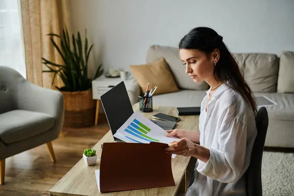 A woman in casual attire working on a laptop at a table. — Stock Photo