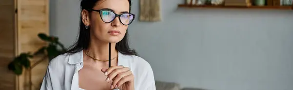 A stylish woman with glasses confidently holds a pen. — Stock Photo