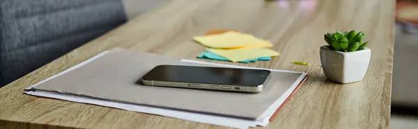 A cell phone rests on a rustic wooden table. — Stock Photo