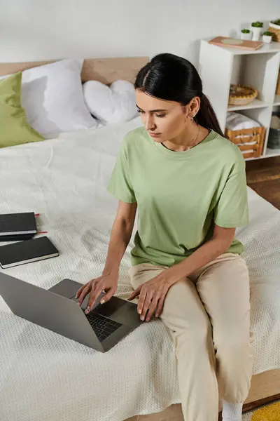Woman in casual attire using laptop on bed — Stock Photo