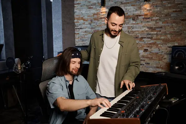 Two men in a recording studio, deeply engrossed, playing a keyboard together during a music band rehearsal. — Stock Photo