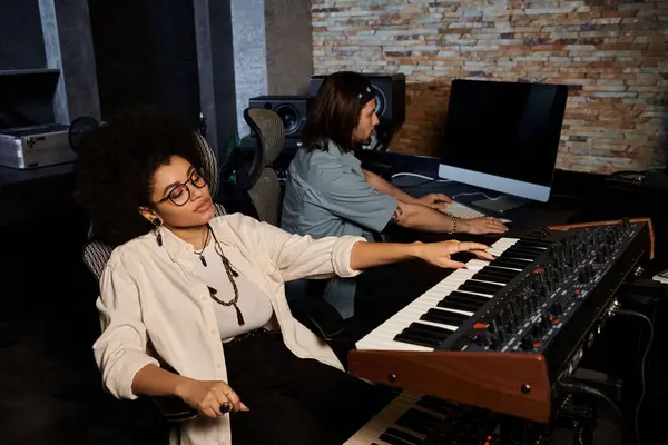 Deux musiciens sont assis dans un studio d'enregistrement, travaillant ensemble sur un clavier, répétant pour leur performance de groupe de musique. — Photo de stock