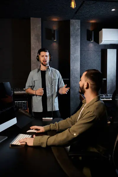 Due uomini in uno studio di registrazione si impegnano in una discussione animata durante una sessione di prove di una band musicale. — Foto stock
