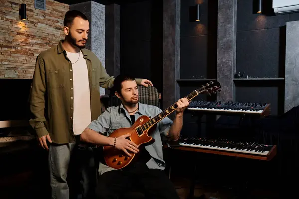 Zwei Männer stehen nebeneinander, eingetaucht in eine Musikband-Probe in einem Tonstudio. — Stockfoto