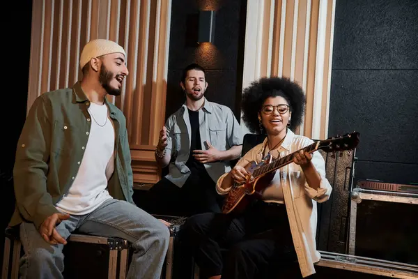 A diverse group of musicians sit in a recording studio, strumming a guitar and deep in musical collaboration. — Stock Photo