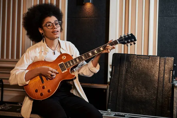 Femme talentueuse joue passionnément de la guitare dans un studio d'enregistrement lors d'une répétition du groupe de musique. — Photo de stock